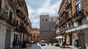 Un carrer estret amb edificis a ambdós costats, alguns amb balcons i plantes en testos.