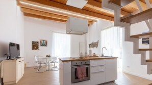 Una cuina moderna amb una illa central, armaris blancs i un sostre de fusta.