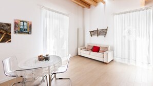 Un saló modern amb una taula rodona de vidre, sofà blanc i bigues de sostre de fusta.