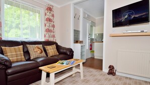A living room with a brown leather sofa, a wooden coffee table, and a television mounted on the wall. - The Bridge Suite, Invermoriston - The Great Glenway (Invermoriston)