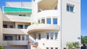 Un immeuble à plusieurs étages, doté de balcons, de grandes fenêtres et surplombant un ciel d’un bleu éclatant.
