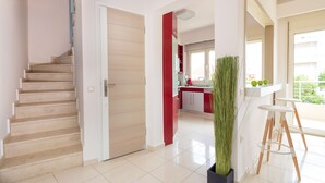Une cuisine moderne avec des meubles blancs, un mur d’accent rouge et une grande fenêtre.