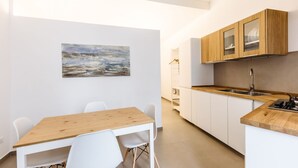 Una cucina moderna con mobili bianchi, un piano di lavoro in legno e un quadro appeso al muro.