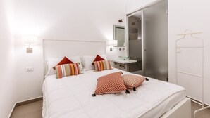 Una camera d'albergo con un letto, un comodino, uno specchio e la porta del bagno.