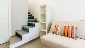 Una scala con una parete bianca e un divano beige con un cuscino decorato.
