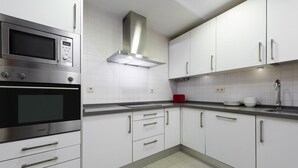Eine moderne Küche mit Edelstahlgeräten, weißen Schränken und einer grauen Arbeitsplatte.