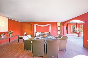 A dining area with wicker furniture, a glass table, and a red-walled interior. - Villa San Michele, Griante - Cadenabbia, Italy (Griante - Cadenabbia)