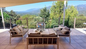 A terrace with outdoor furniture, a barbecue, and a view of mountains.