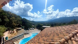 A rooftop pool with a clear view of the surrounding landscape, including trees and distant mountains.