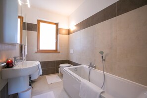 Een bad/douchecombinatie, een haardroger, een bidet, handdoeken