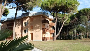 Un immeuble à plusieurs étages doté de balcons, entouré d’arbres et d’une zone herbeuse.