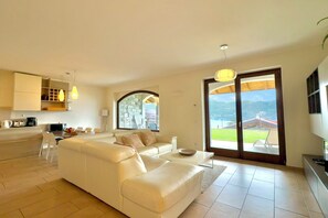 A spacious living area with a white sofa, a dining table, and a kitchen area with a built-in oven and microwave.
