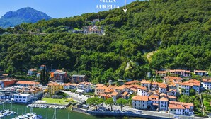 A coastal town with buildings, a marina, and a hill in the background. - Villa Aurelia, Plesio, Italy (Plesio)