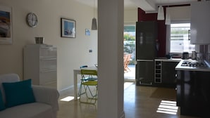 A modern kitchen with a refrigerator, stove, and dining area with chairs and a table. - Modern Villa with pool, sea view and mediterranean garden (Bari)