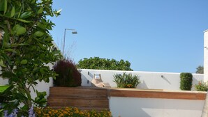 A rooftop garden with wooden steps, various plants, and a white wall. - Modern Villa with pool, sea view and mediterranean garden (Bari)