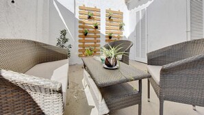 Une terrasse dotée de meubles en osier, d’une table agrémentée d’une plante en pot et d’un mur en bois servant de jardinière, orné de fleurs.