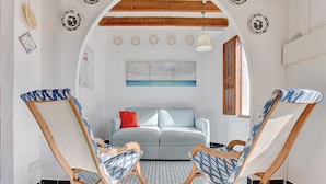 Une pièce avec un canapé bleu clair, deux fauteuils à bascule dotés de coussins à motifs, un ventilateur de plafond et un luminaire fixé au mur.