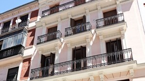A multi-story building with balconies, large windows, and a storefront with mannequins.