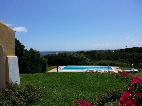 A swimming pool with a clear view of the sea and hills in the background.