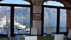 Habitación con una ventana grande que da a un puerto deportivo con barcos y montañas.