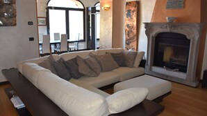 Una sala de estar con un sofá seccional, una chimenea y un comedor al fondo.