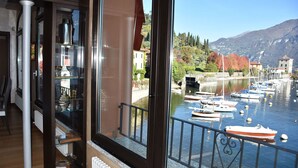 Vista desde un balcón con vista a un lago con barcos, una montaña al fondo y un edificio con techo rojo.