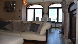 Una sala de estar con un sofá, una chimenea y ventanas amplias.