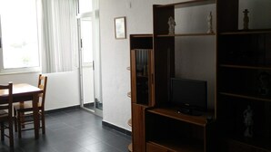 Ein Wohnzimmer mit einer Holzeinrichtungsanlage, einem Fernseher und einem Essbereich mit Tisch und Stühlen.
