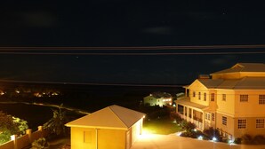 A large, two-story house with a well-lit driveway and a gated entrance. - Ocean view apartment with plunge pools, roof terrace, balcony and near the beach (Enterprise)