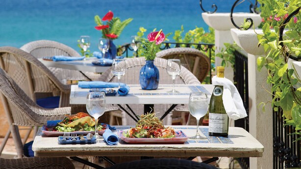 An outdoor dining area with a table set for two, overlooking the sea. - Ocean view apartment with plunge pools, roof terrace, balcony and near the beach (Enterprise)