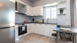 Eine moderne Küche mit Edelstahlgeräten, weißen Schränken und einem Essbereich mit Tisch und Stühlen.
