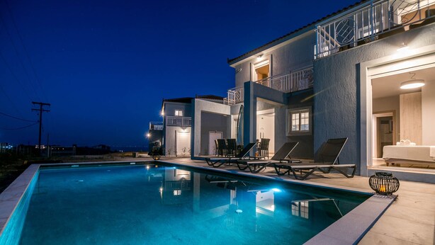 Ein modernes Haus mit Swimmingpool, Sitzgelegenheit im Freien und einem Balkon.