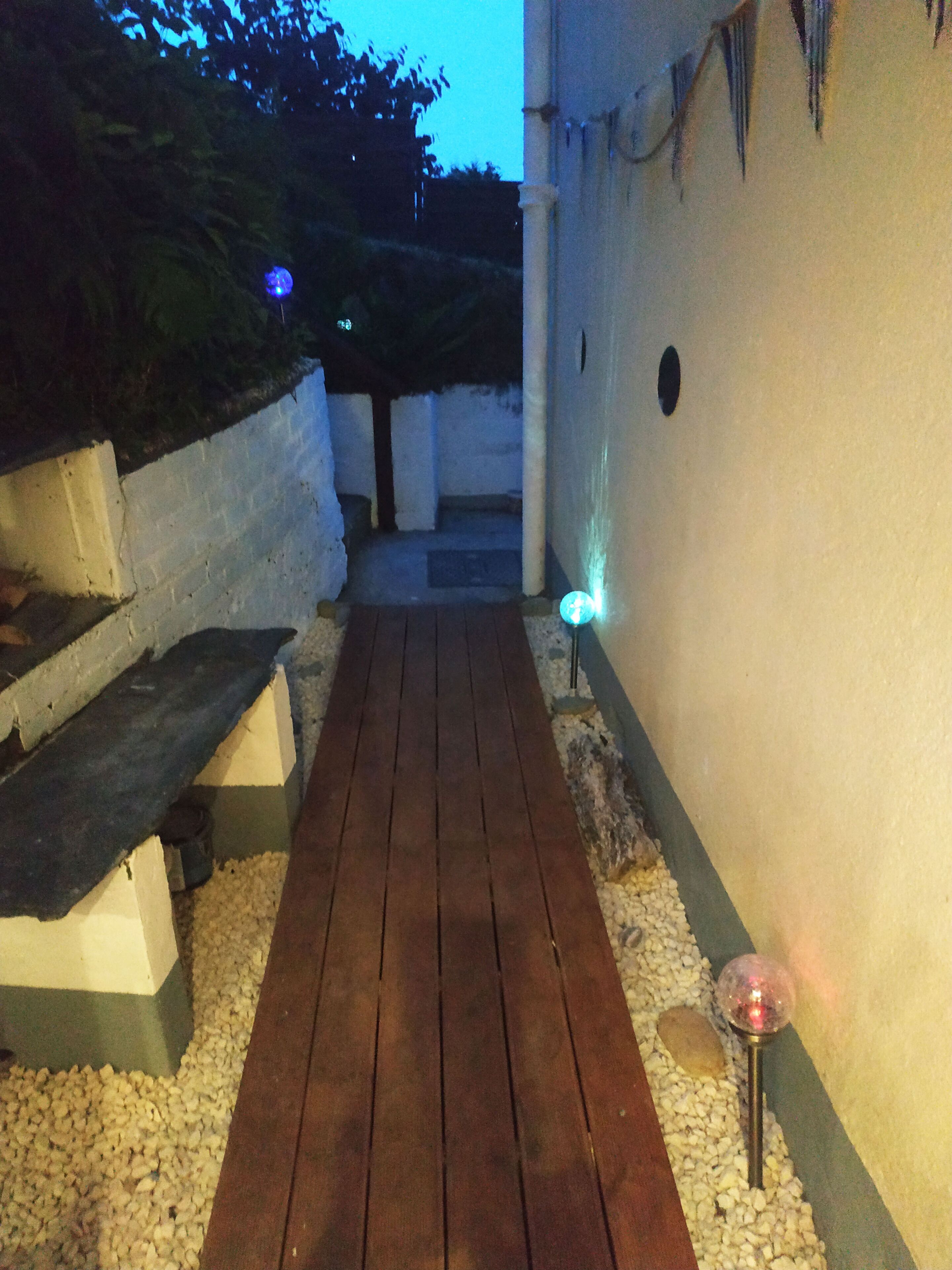 Ein hölzerner Weg führt zu einem weißen Gebäude mit einer kleinen Veranda.