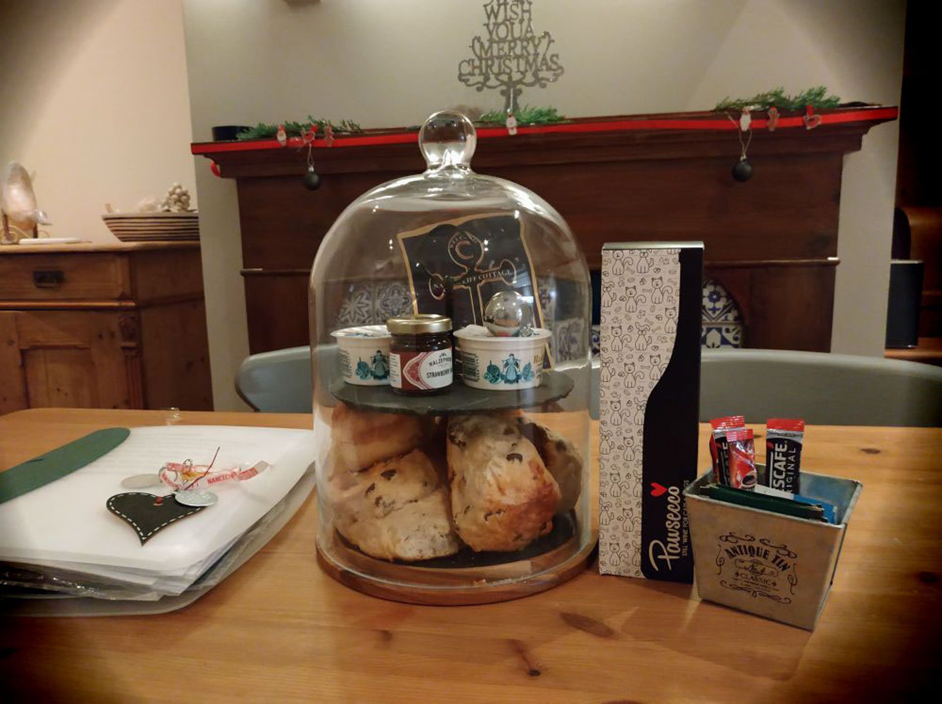 A table with a glass dome displaying pastries, a box of tea, and a decorative item.