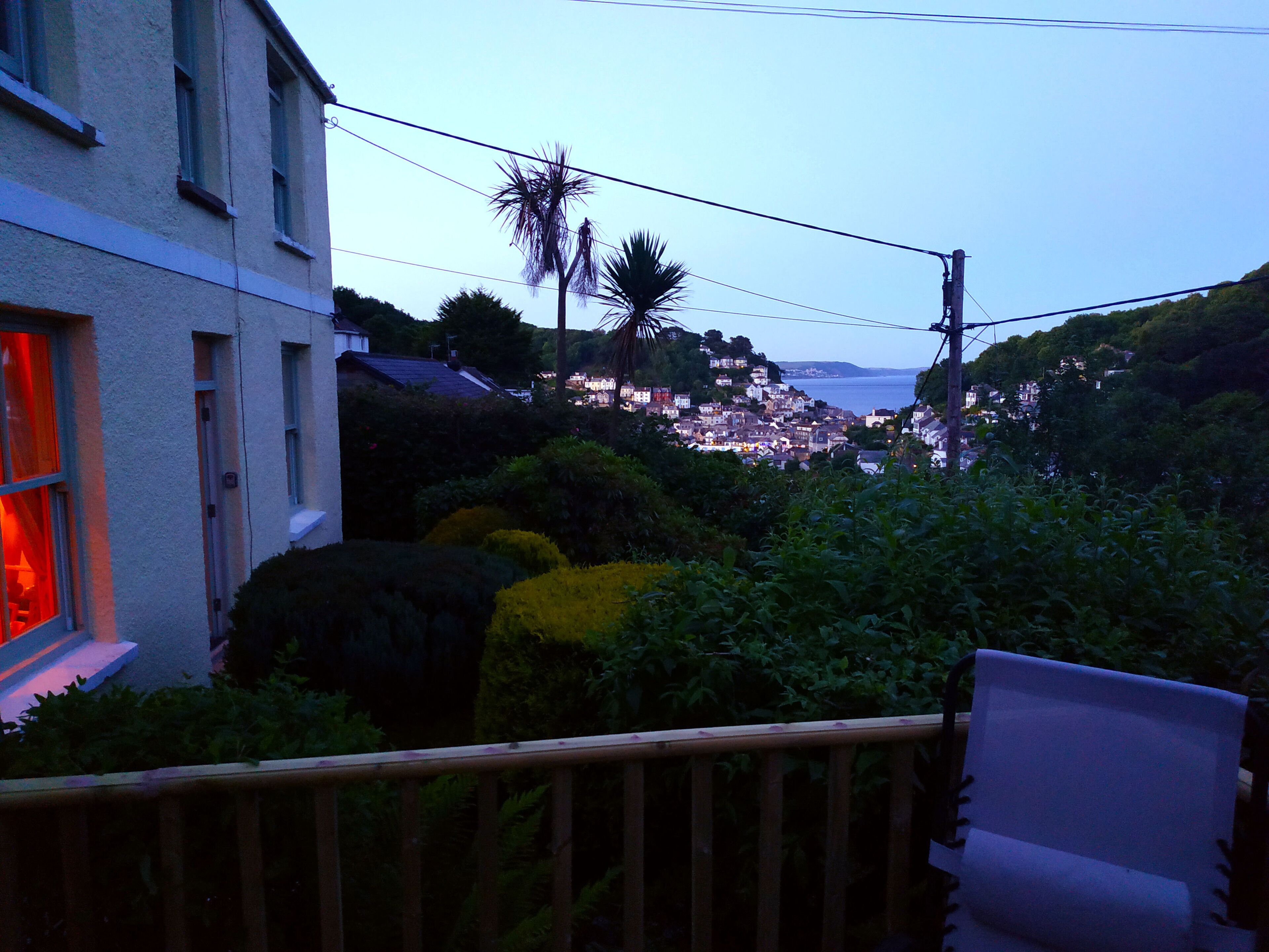 A balcony with a view of a coastal town at dusk.