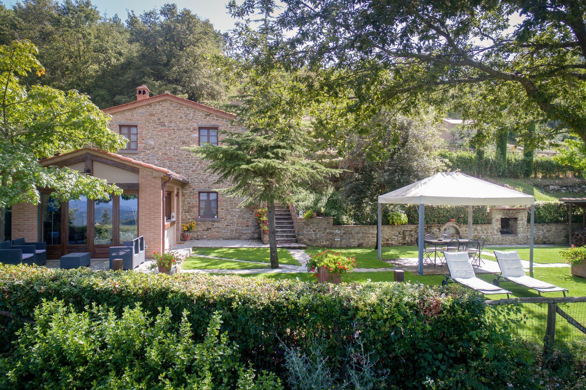 A stone house with a patio, outdoor seating, and a barbecue area.