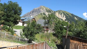 Et bjerg med et hus i forgrunden og et træhegn.