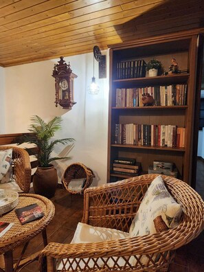 Une pièce chaleureuse, meublée de meubles en osier, avec une bibliothèque et une horloge murale.