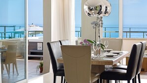 A dining area with a view of the sea, large windows, and a modern chandelier. - Apt 401 Luxury Serv Aparts-Estepona, 3 Bed, Heated 20m Pool, Jacuzzi - an Oasis (Estepona)