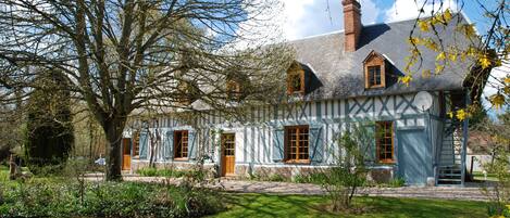 A traditional half-timbered house with a chimney, a wooden door, and a small staircase leading to the entrance.