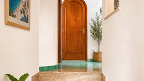 A staircase with a wooden door at the top, a potted plant, and a framed picture on the wall. - AMORE RENTALS - Casa Raffi with Sea View on Positano’s Spiaggia Grande (Positano)