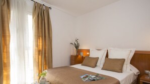 A hotel room with a bed, bedside table, and a window with curtains. - Singular Stays Poeta Querol (València)