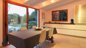 Eine moderne Küche mit Essbereich, großen Fenstern und Blick ins Freie.
