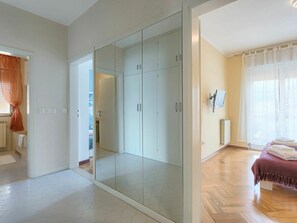 Quarto com cama, guarda-roupa e banheiro visível por uma porta aberta.