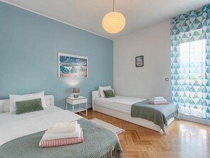 A bedroom with two beds, a nightstand, a lamp, and a painting on the wall.
