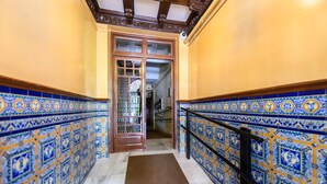 Un pasillo con baldosas de diseño azul y amarillo, una puerta de madera y un felpudo marrón.