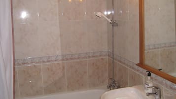 Een bad/douchecombinatie, een haardroger, handdoeken, toiletpapier