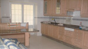 Una cocina con armarios de madera, encimera de granito y ventana con cortinas.