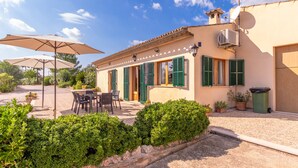 A villa with outdoor seating, a satellite dish, and a well-maintained garden.