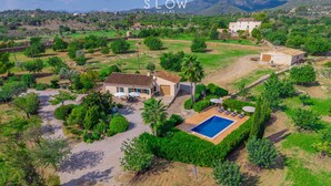 A villa with a swimming pool, surrounded by lush greenery and a mountainous backdrop.